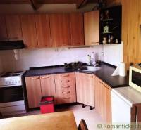 Chata nad kúpeľmi Dudince s vlastným pozemkom - Kuchyňa v chate s podlahou s dreveným dekorom, varnou doskou a mikrovlnkou.