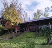 Chata nad kúpeľmi Dudince s vlastným pozemkom - Chata v Dudinciach obklopená prírodou s terasou a stromami na dvore.