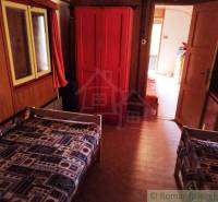 Chata nad kúpeľmi Dudince s vlastným pozemkom - Interiér chaty s dvomi lôžkami, červenou skriňou a kobercom s geometrickým vzorom.