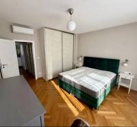 Prenájom pekný 3 izbový byt, Dunajská ulica, Bratislava I. Staré Mesto - Spálňa s posteľou, skriňou a podlahou s dreveným dekorom v 3-izbovom byte.