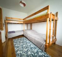 Rodinný dom s veľkým pozemkom v obci Sklené,  - Poschodová posteľ v rodinnom dome s podlahou s dreveným dekorom a vzorovaným kobercom.