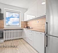 NA PRENÁJOM 2x 2-IZBOVÉ BYTY S TERASOU,DUNAJSKÁ STREDA - Biela kuchyňa v 2-izbovom byte s podlahou s dreveným dekorom a výhľadom z okna.