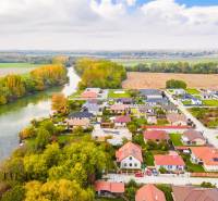 NA PREDAJ INVESTIČNÝ STAVEBNÝ POZEMOK, JAHODNÁ - Pohľad na Developerské pozemky v Jahodnej pri rieke, obklopené zeleňou a domami.