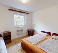 Rekreačná chata Šaštín-Stráže Gazárka komerčné využitie - Spálňa v chate s tromi lôžkami, nočný stolík a okno s výhľadom.