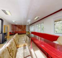 Rekreačná chata Šaštín-Stráže Gazárka komerčné využitie - Izba v chate s kachľami, pohovkami, drevenými stolmi a výhľadom na les.