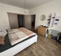 Veľký 96 m2  2 izbový byt s garážovým státím Topoľčany Centrum  - Spálňa v 2-izbovom byte s podlahou s dreveným dekorom, posteľou a úložným priestorom.