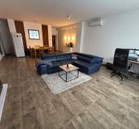 Veľký 96 m2  2 izbový byt s garážovým státím Topoľčany Centrum  - Obývacia izba v 2-izbovom byte s modrou sedačkou a pracovným stolom.