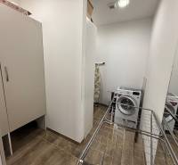 Veľký 96 m2  2 izbový byt s garážovým státím Topoľčany Centrum  - Výklenok s práčkou, sušiakom a skriňou v 2-izbovom byte; podlaha s dreveným dekorom.