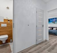 REZERVOVANÉ Predaj moderný 1-izbový byt, 45,24m2, Bratislava IV - Chodba v 1-izbovom byte s toaletou a podlahou s dreveným dekorom.