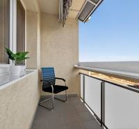 REZERVOVANÉ Predaj moderný 1-izbový byt, 45,24m2, Bratislava IV - Balkón na Milana Marečka v Bratislave - Devínskej Novej Vsi s kreslom a rastlinou.