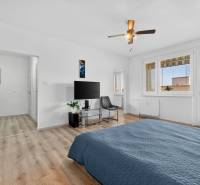 REZERVOVANÉ Predaj moderný 1-izbový byt, 45,24m2, Bratislava IV - Spálňa v 1-izbovom byte s televízorom, kreslom a podlahou s dreveným dekorom.