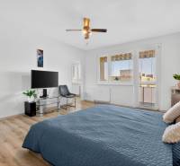 REZERVOVANÉ Predaj moderný 1-izbový byt, 45,24m2, Bratislava IV - Spálňa s posteľou, televízorom, kreslom, rastlinou a podlahou s dreveným dekorom v 1-izbovom byte.