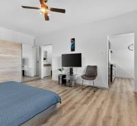 REZERVOVANÉ Predaj moderný 1-izbový byt, 45,24m2, Bratislava IV - Jednoizbový byt s podlahou s dreveným dekorom, posteľou a televízorom na stene.