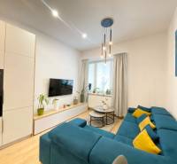 NA PRENÁJOM ŠTÝLOVÝ 2-IZBOVÝ BYT V CENTRE KOŠÍC, DREVNÝ TRH - Obývačka v 2-izbovom byte s modrou sedačkou a podlahou s dreveným dekorom.