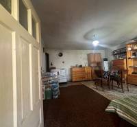 !! NOVÁ CENA !! predaj romantickej chalúpky v Šípkove  - Interiér s dreveným nábytkom, kobercom, stolom a chata dodáva rustikálnu atmosféru.