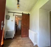 !! NOVÁ CENA !! predaj romantickej chalúpky v Šípkove  - Interiér chaty s podlahou s dreveným dekorom, radiátorom a jazdnou drevenou dverou.