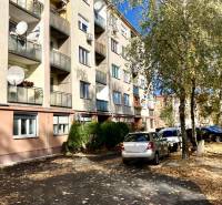 3-izbový byt s loggiou v širšom centre, Komárno - Bytový dom na Mederčskej v Komárne so zaparkovanými autami a stromami.