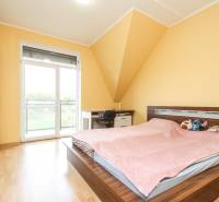 4i mezonet, 133m2, vlastné kúrenie, Melčice-Lieskové - Spálňa v 4-izbovom byte s posteľou, skriňou a podlahou s dreveným dekorom.