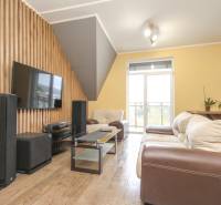 4i mezonet, 133m2, vlastné kúrenie, Melčice-Lieskové - Obývacia izba so sedačkou, televízorom a podlahou s dreveným dekorom v 4-izbovom byte.