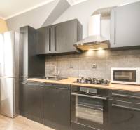 4i mezonet, 133m2, vlastné kúrenie, Melčice-Lieskové - Kuchyňa v 4-izbovom byte s čiernymi skrinkami a podlahou s dreveným dekorom.