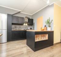 4i mezonet, 133m2, vlastné kúrenie, Melčice-Lieskové - Kuchyňa v 4-izbovom byte s ostrovom, čiernymi skrinkami a podlahou s dreveným dekorom.