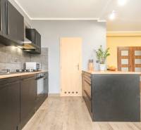 4i mezonet, 133m2, vlastné kúrenie, Melčice-Lieskové - Kuchyňa v 4-izbovom byte s čiernymi skrinkami a podlahou s dreveným dekorom.