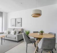 Novostavba Apartmán La Mata, 78m2, bazén, garáž - Svetlá obývacia izba Rekreačného apartmánu so sivým kreslom a dreveným stolom.