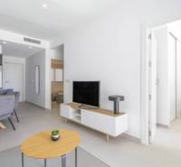 Novostavba Apartmán La Mata, 78m2, bazén, garáž - Rekreačný apartmán s otvorenou obývacou izbou, jedálenským stolom a podlahou s dreveným dekorom.