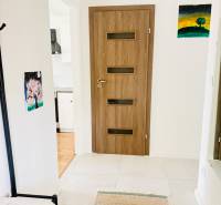 Novostavba 3i bytu s parkovaním, Dvorníky - Vstupná chodba v 3-izbovom byte s keramickou dlažbou, zavesenými obrazmi a masívnymi dverami.