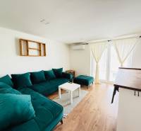 Novostavba 3i bytu s parkovaním, Dvorníky - Svetlá obývačka so zelenou sedačkou v 3-izbovom byte a podlaha s dreveným dekorom.