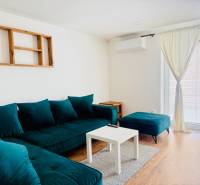 Novostavba 3i bytu s parkovaním, Dvorníky - Obývačka v 3-izbovom byte s tyrkysovým nábytkom a podlahou s dreveným dekorom.