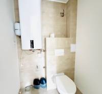 Novostavba 3i bytu s parkovaním, Dvorníky - Toaleta a bojler v kúpeľni 3-izbového bytu s dlažbou na podlahe.