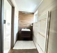 Novostavba 3i bytu s parkovaním, Dvorníky - Kúpeľňa v 3-izbovom byte s umývadlom, podlahou s dreveným dekorom a rebríkovým radiátorom.