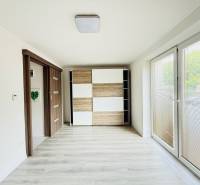 Novostavba 3i bytu s parkovaním, Dvorníky - Svetlá obývacia izba trojizbového bytu s veľkými oknami a podlahou s dreveným dekorom.