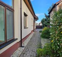 REZERVOVANÉ! Predáme 5-izbový rodinný dom na Štúrovej ulici, Vráble - Pohľad na bočnú časť rodinného domu v Štúrovej ulici vo Vrábľoch s dláždeným chodníkom.