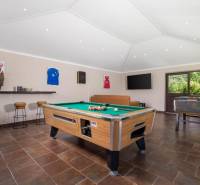 Na predaj KAMENNÝ DOM s LUXUSOM v srdci Istrie - Interiér vily s biliardovým stolom, koženou sedačkou a podlahou s dreveným dekorom.