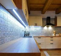 LUKRATÍVNA CHATA - NOVOSTAVBA - SRDCE VRÁTNEJ DOLINY - Kuchyňa v chate s dlaždicami a podlahou s dreveným dekorom, osvetlená LED svetlami.