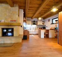 LUKRATÍVNA CHATA - NOVOSTAVBA - SRDCE VRÁTNEJ DOLINY - Interiér chaty s kachľovým krbom, dreveným stropom a podlahou s dreveným dekorom.