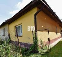 Rodinný dom s veľkým pozemkom o výmere 3271m2 na predaj - Rodinný dom v Partizánskej Ľupči, žltá fasáda, starý plot s pletivom.