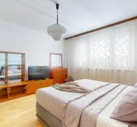 Z vchodu rovno do školy, na predaj praktický 3 izbový byt, Andrusovova - Spálňa v 3-izbovom byte s podlahou s dreveným dekorom, závesmi a nábytkom.