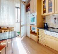 Z vchodu rovno do školy, na predaj praktický 3 izbový byt, Andrusovova - Kuchyňa v 3-izbovom byte s podlahou s dreveným dekorom a vstupom na lodžiu.