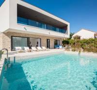 NA PREDAJ novo postavená VILA  /200 m2/ pri mori, Rogoznica - Vila v Bale s bazénom a ležadlami, obklopená zeleňou a modrou oblohou.