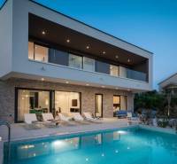 NA PREDAJ novo postavená VILA  /200 m2/ pri mori, Rogoznica - Vila v Bale s bazénom, ležadlami a terasou počas súmraku.