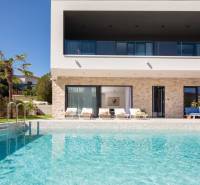 NA PREDAJ novo postavená VILA  /200 m2/ pri mori, Rogoznica - Vila v Bale s bazénom, palmami, terasou a ležadlami na pozadí.