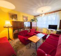 REZERVOVANÉ- Na predaj 3-izbový byt Žilina-Vlčince - Obývačka 3-izbového bytu s červenými sedačkami, koberec, dekorácie na stene, drevený nábytok.