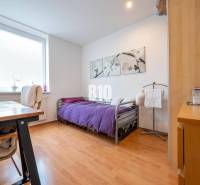 Príjemný 4 izbový byt s balkónom - Klokočina - Spálňa v 4-izbovom byte s podlahou s dreveným dekorom a fialovým prehozom.