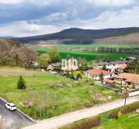 Jelenec  - Nádherný pozemok pri lese - 687 m2 - Pozemky - bývanie v Jelenci obklopené prírodou a rodinnými domami, s lesnatými kopcami v pozadí.