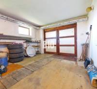 Rodinný dom s nádherným 8 árovým pozemkom na Kamennej ulici - Garáž v rodinnom dome s drevenými dverami a podlahou podobnou drevenému dekoru.