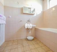 Rodinný dom s nádherným 8 árovým pozemkom na Kamennej ulici - Kúpeľňa v rodinnom dome s vaňou a svetlými obkladmi na stenách.