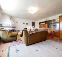 Rodinný dom s nádherným 8 árovým pozemkom na Kamennej ulici - Obývacia izba s krbom a retro nábytkom v rodinnom dome, podlaha s dreveným dekorom.